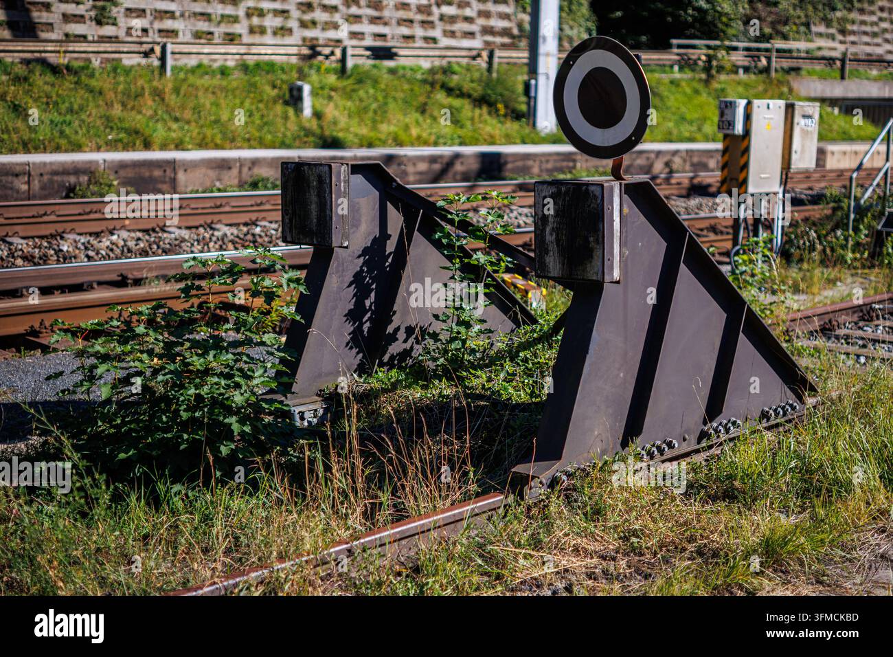Eine Nahaufnahme von Bahnsteigausrüstung, einschließlich eines runden Signals und dreieckiger Weichen, vor dem Hintergrund von Bahngleisen Stockfoto