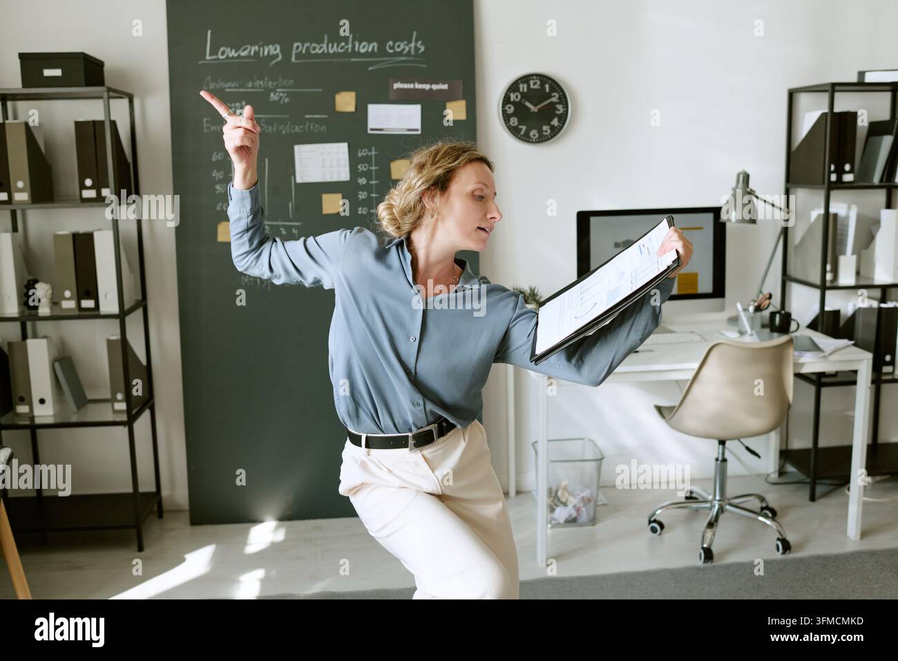 Fröhliche Geschäftsfrau tanzt mit Berichtsdokument im modernen Büro Stockfoto