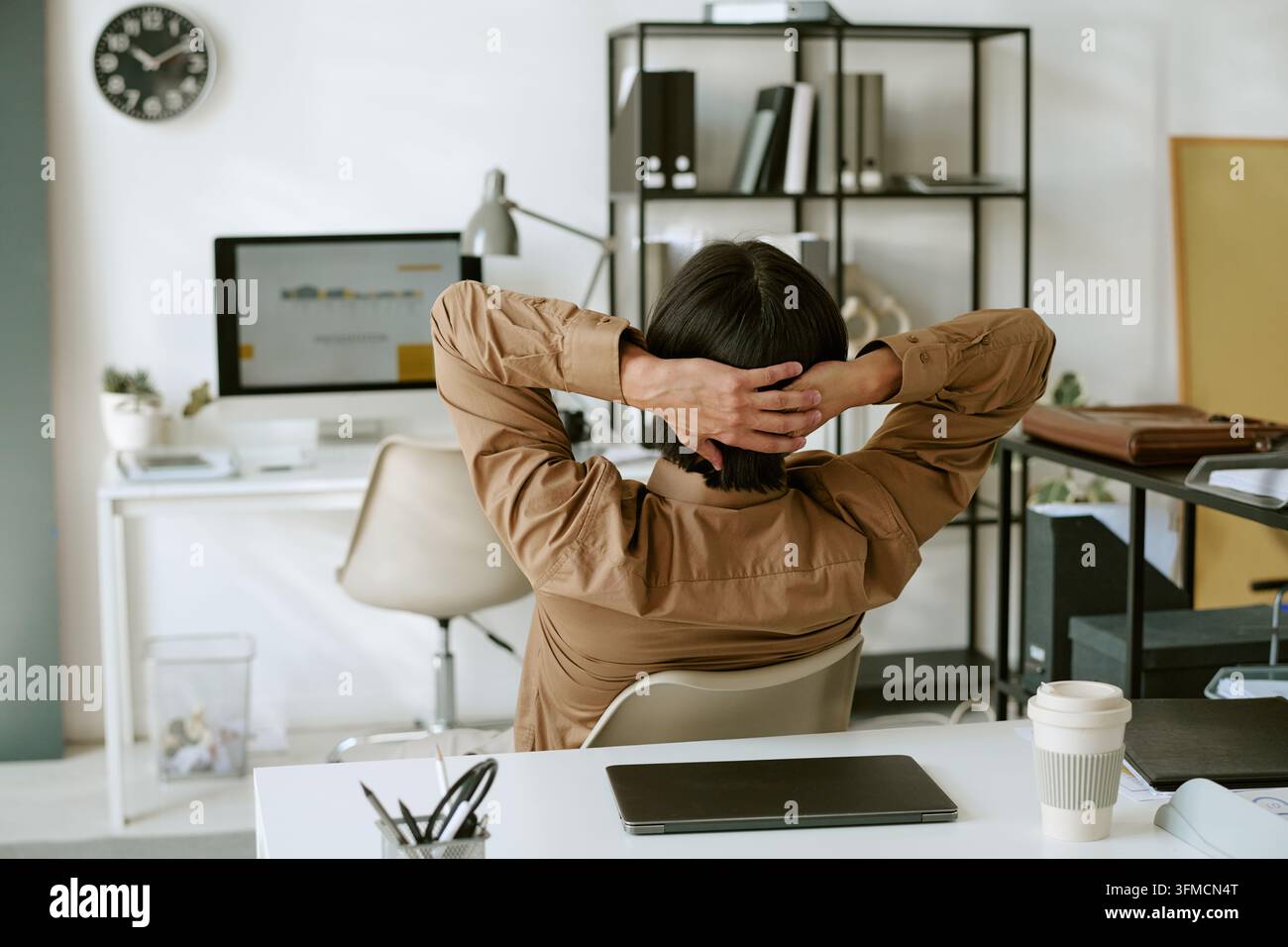 Geschäftsmann entspannt mit Händen hinter dem Kopf am Bürotisch Stockfoto