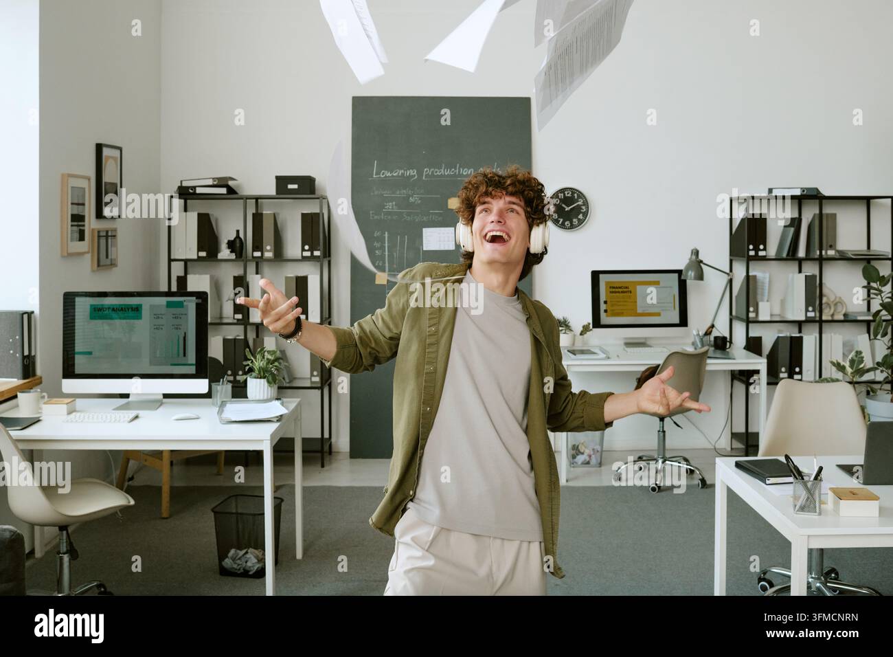 Fröhlicher Geschäftsmann tanzt und wirft Papiere im Büro Stockfoto