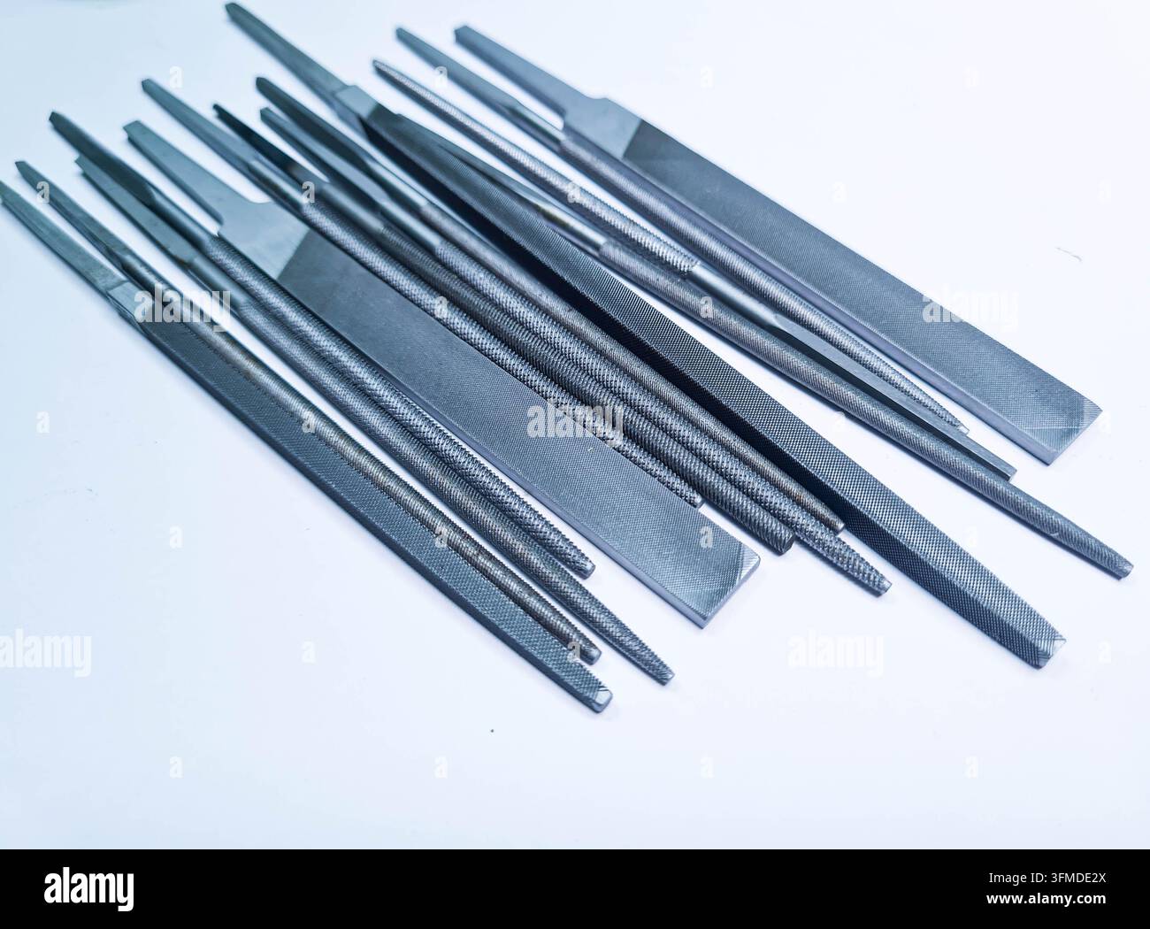Verschiedene Metallfeilen in unterschiedlichen Formen, die auf einem sauberen weißen Hintergrund angeordnet sind, geeignet für industrielle, werkstattbezogene, handwerkliche und technische Konzepte. Stockfoto