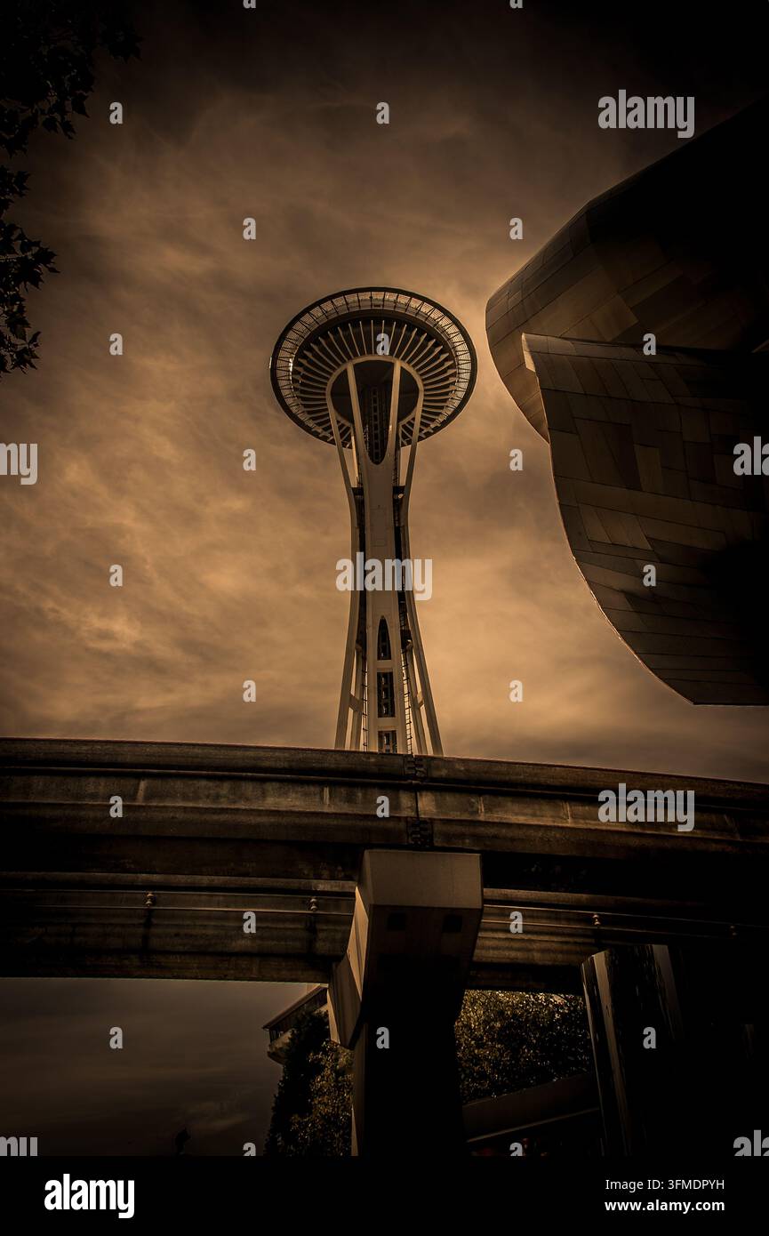Blick auf die Space Needle und das Museum of Pop Culture mit der Monorail-Schiene im Vordergrund unter einem dramatischen bewölkten Himmel in Seattle, Washington, U Stockfoto