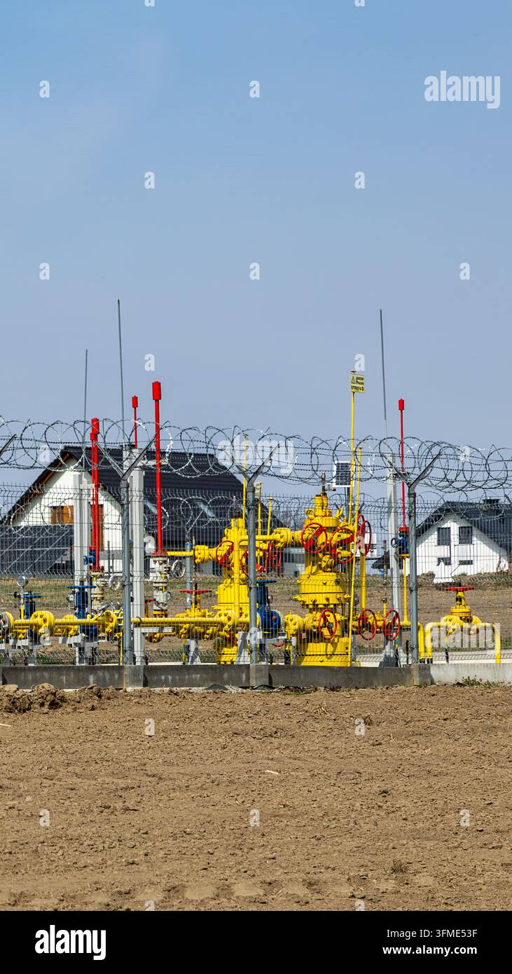 Gasinfrastruktur mit Pipelines und Industrieausrüstung neben einem Feld Stockfoto