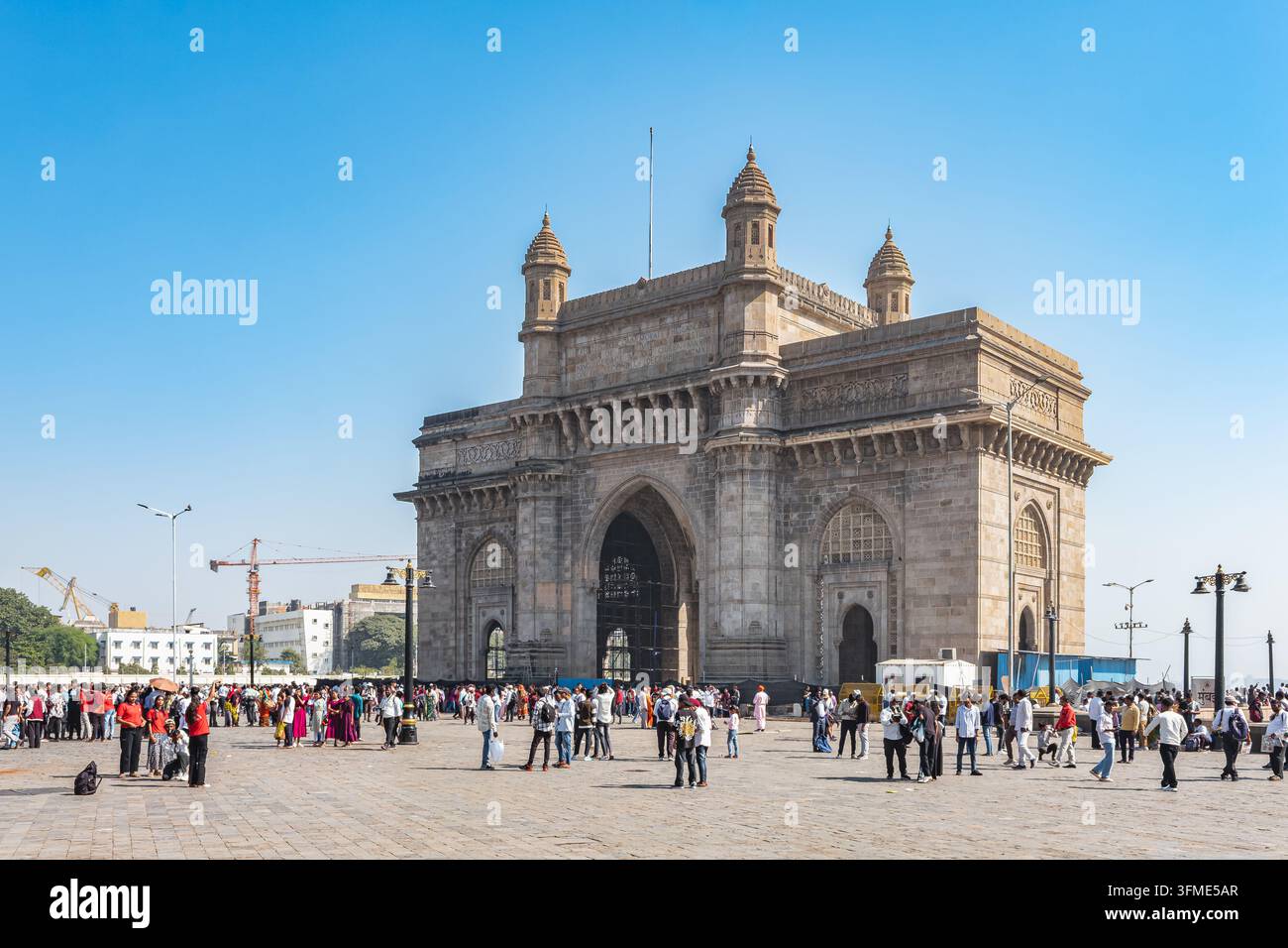 Gateway of India und viele Touristen laufen um die Monumentstruktur an einem sonnigen Sommertag. Menschenmenge an der historischen Stätte von Mumbai, Indien, Dez Stockfoto