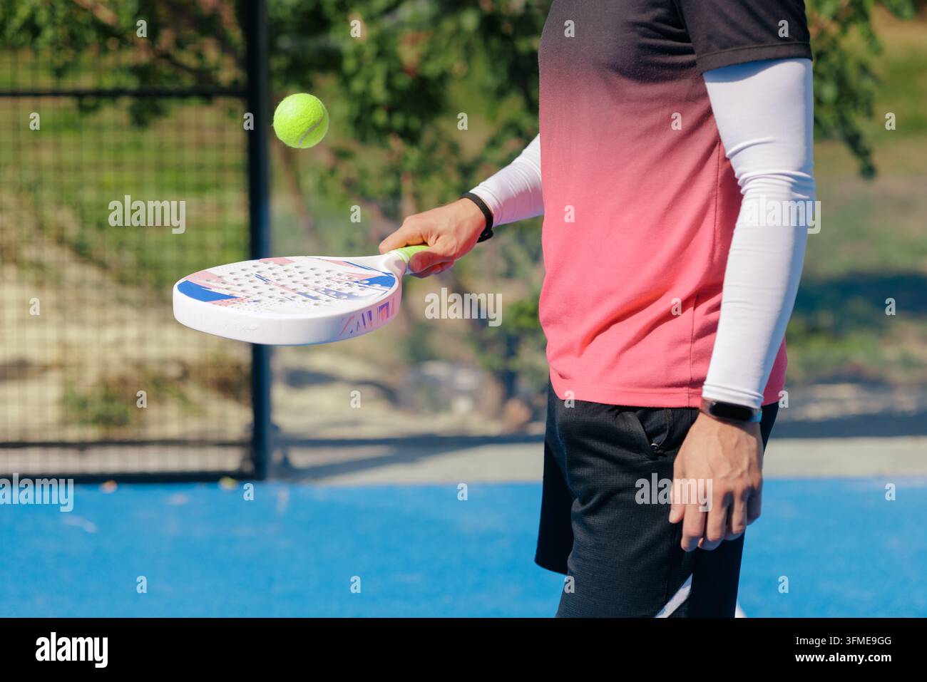 Padel-Spieler übt die Ballkontrolle mit einem Schläger auf einem Außenplatz und veranschaulicht Aufwärmen, Technikentwicklung und Vorbereitung auf das Sporttraining Stockfoto