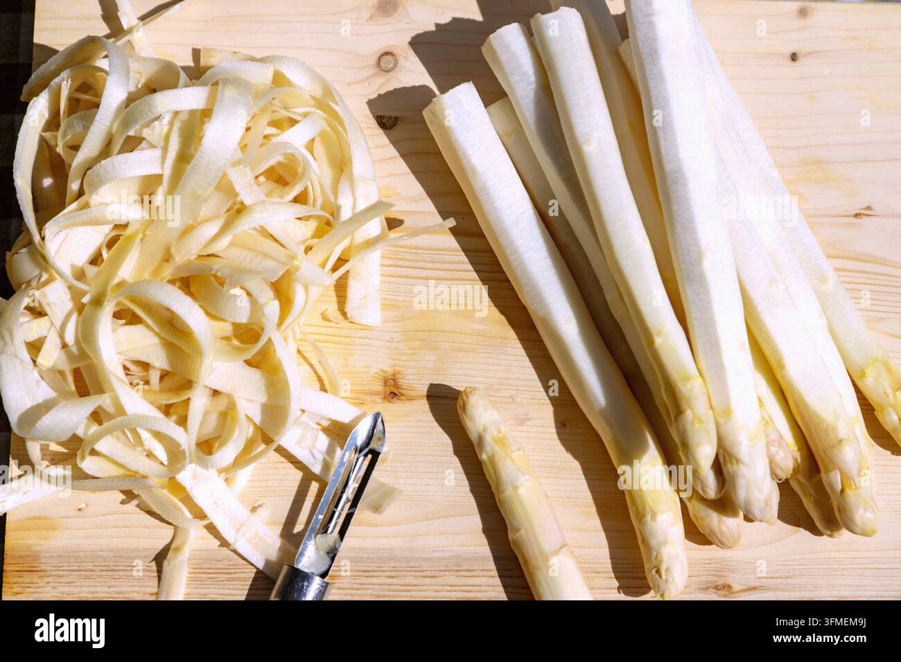 Weißer Spargel, geschält, mit Schäler auf einer Holzbretter im Freien Stockfoto