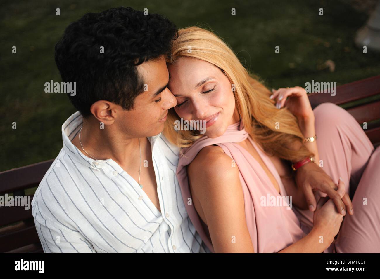 Ein Paar genießt einen zärtlichen Moment in einem sonnigen Park Stockfoto