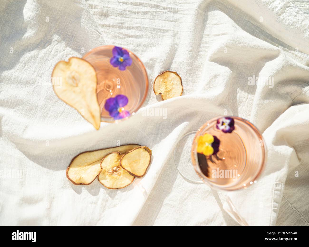 Minimalistische Stillleben mit Wein, Trockenfrüchten und essbaren Blüten im sanften Sonnenlicht. Stockfoto