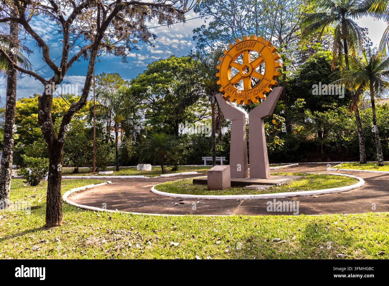 Assis, SP. Brasilien. 28. September 2026: Ein öffentliches Denkmal mit dem ikonischen goldenen Rad-Symbol von Rotary International, gehalten von einer Betonskulptur Stockfoto