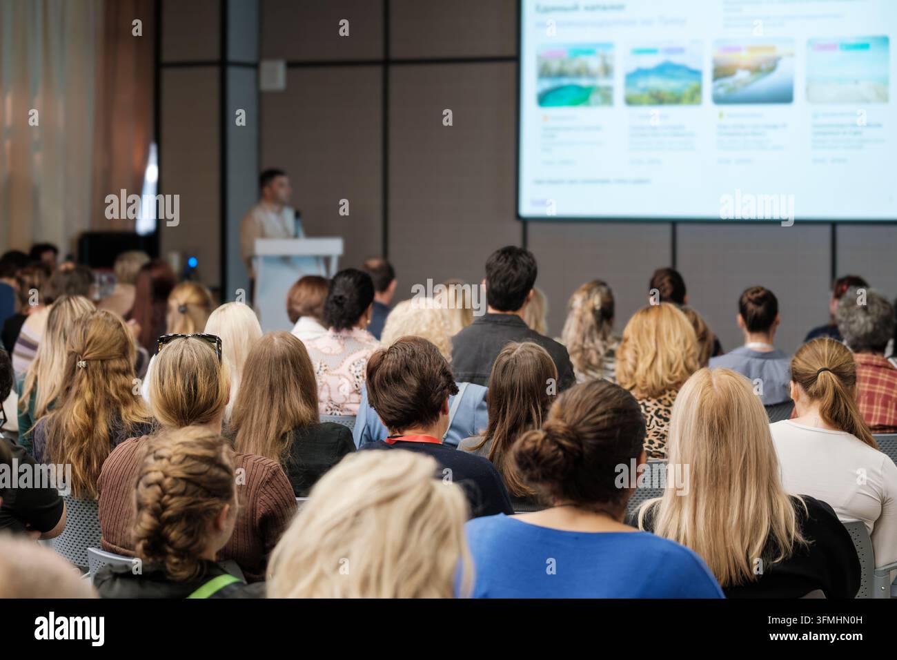 Teilnehmer eines Tourismus-Seminars sehen sich projizierte Reisefotografien während einer Präsentation im Innenraum an. Stockfoto