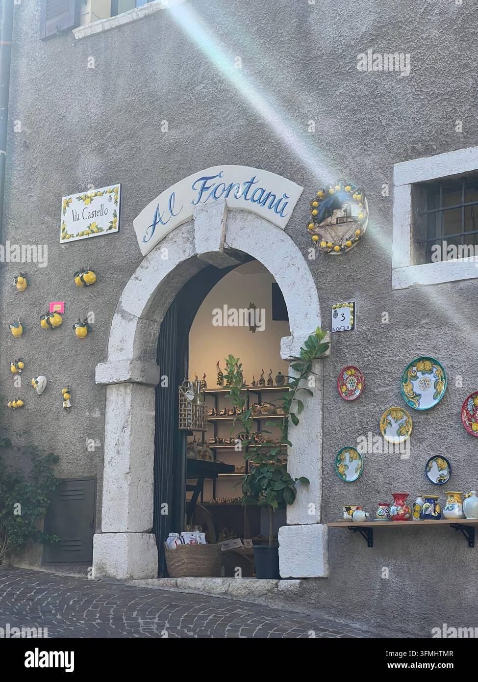 Alter gewölbter Ladeneingang, dekoriert mit handbemalten Keramiktellern in Limone sul Garda, Italien - Smartphone-aufgenommenes Stockfoto