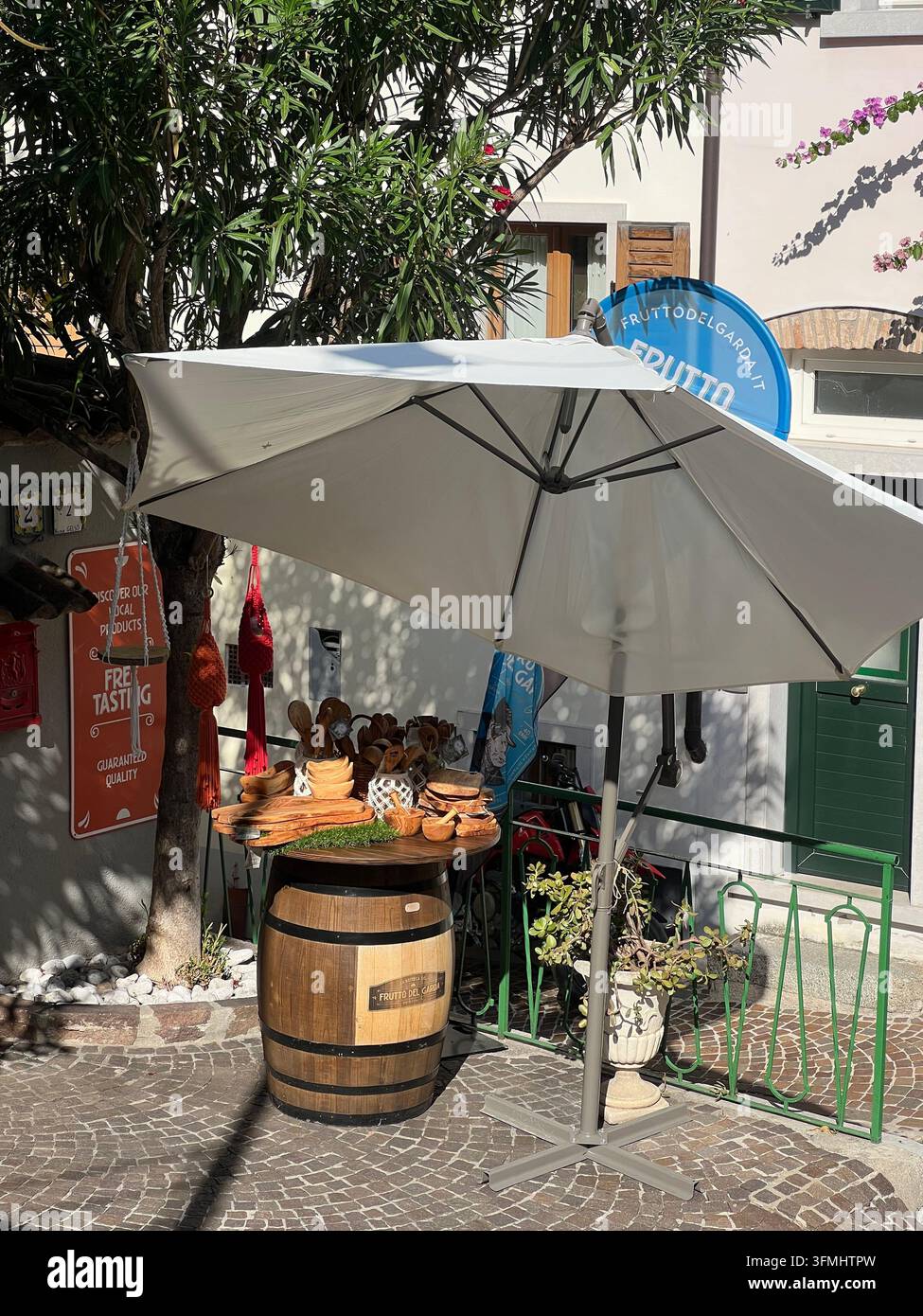 Outdoor-Aperitivo-Café mit einem Holzfass und einem Schirm in Limone sul Garda, Italien - Smartphone-aufgenommenes Stockfoto