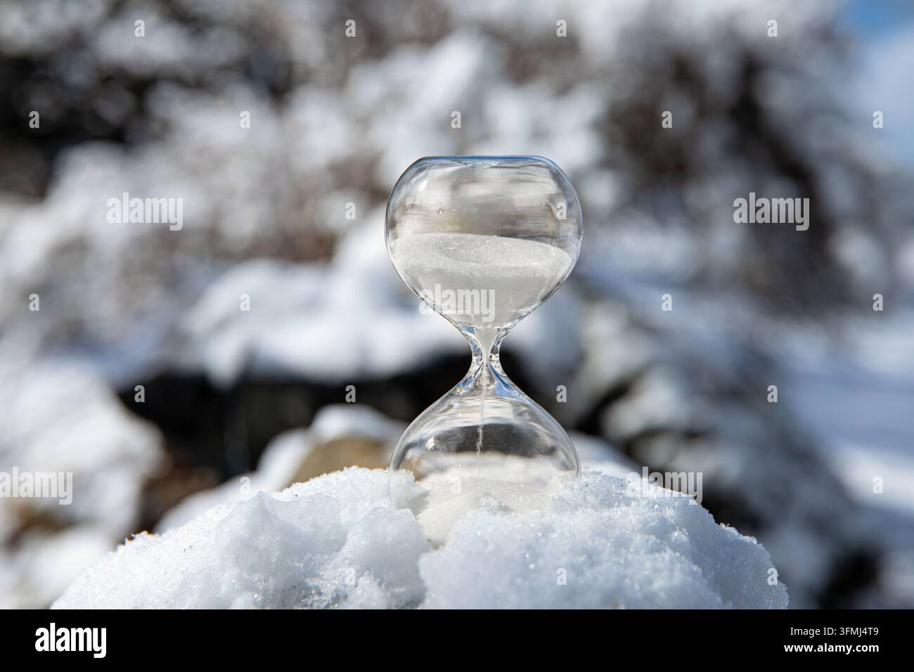 Konzeptionelle Darstellung des Wechsels zur Winterzeit oder des Zurückfallens, Ende der Sommerzeit. Selektiver Fokus auf eine Sanduhr mit weißem Sand, der fällt. Stockfoto