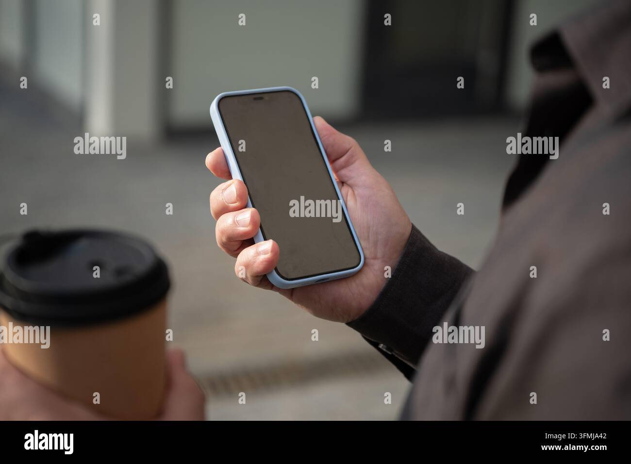 Smartphone in der Hand mit Kaffee im Freien Stockfoto