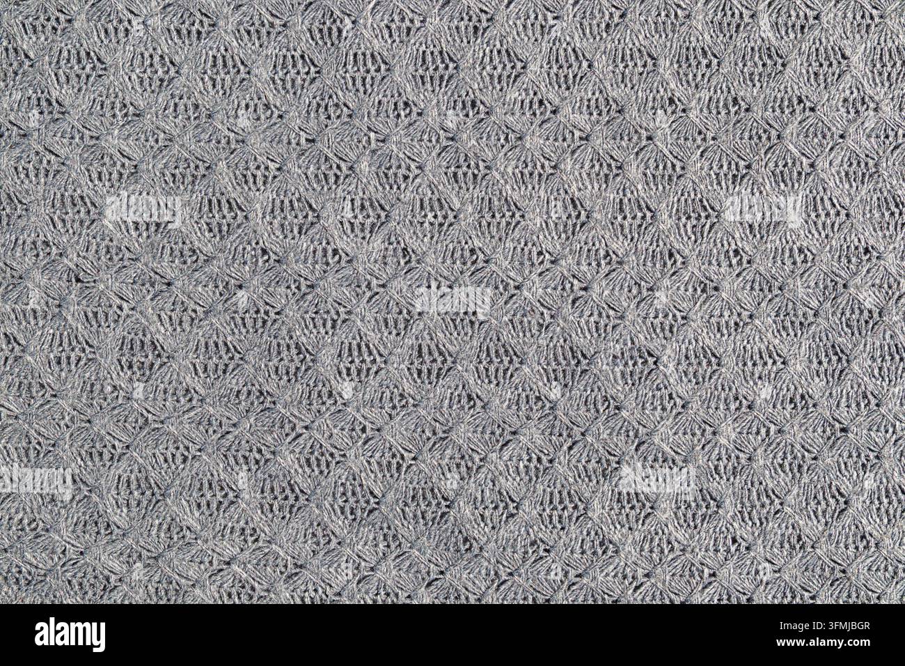 Grauer gestrickter Strukturstoff mit geometrischem Häkelmuster als Hintergrund und nahtlos wiederholbar Stockfoto
