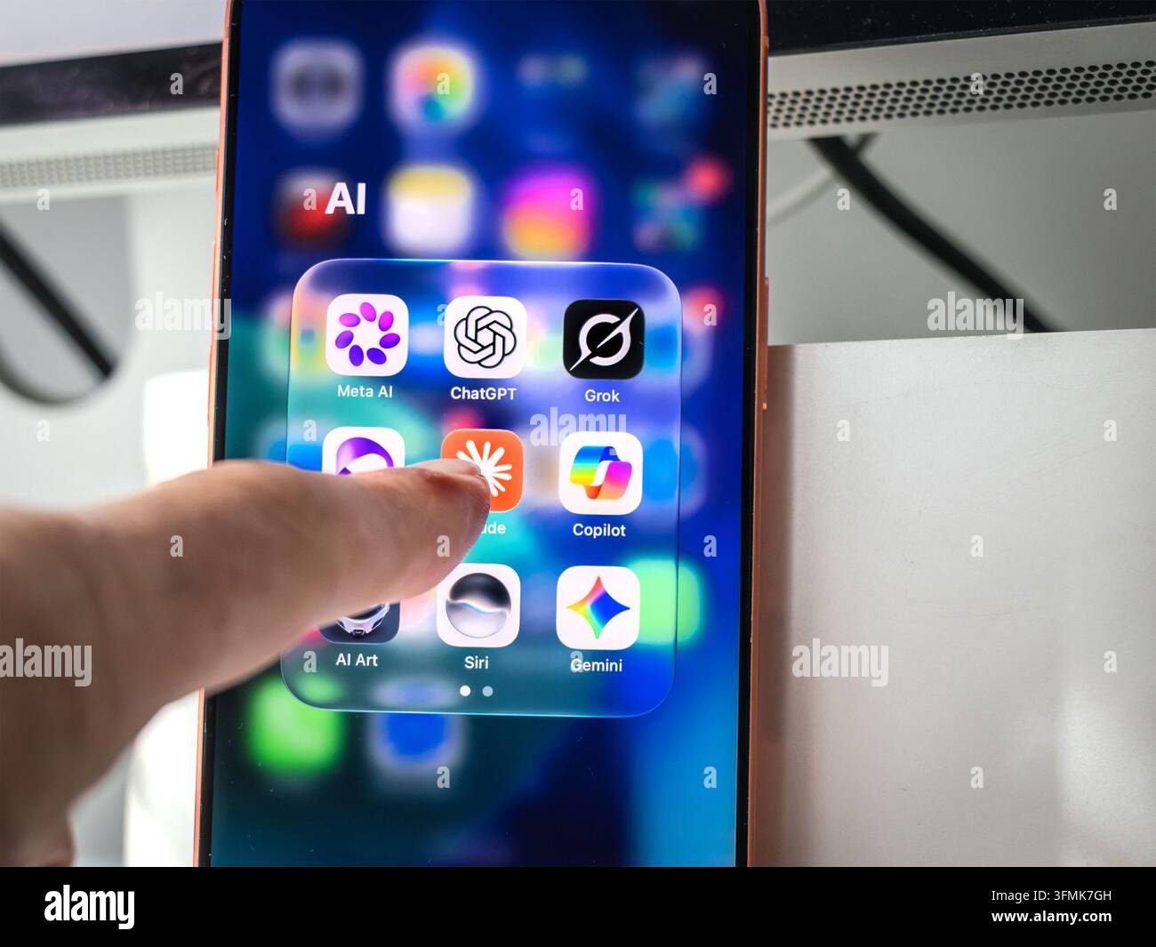Finger berührt Smartphone-Bildschirm mit Ordner von KI-App-Symbolen inklusive ChatGPT, Claude, Meta AI, Grok, Copilot und Siri Stockfoto