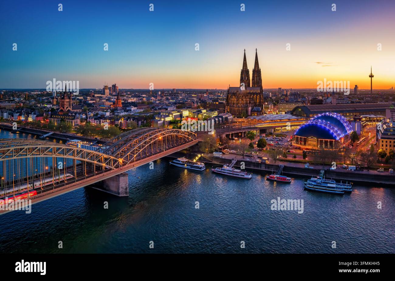 Panoramische Luftaufnahme der beleuchteten Stadtlandschaft von Köln, Deutschland, mit dem Rhein und der berühmten Kathedrale während der Dämmerung Stockfoto