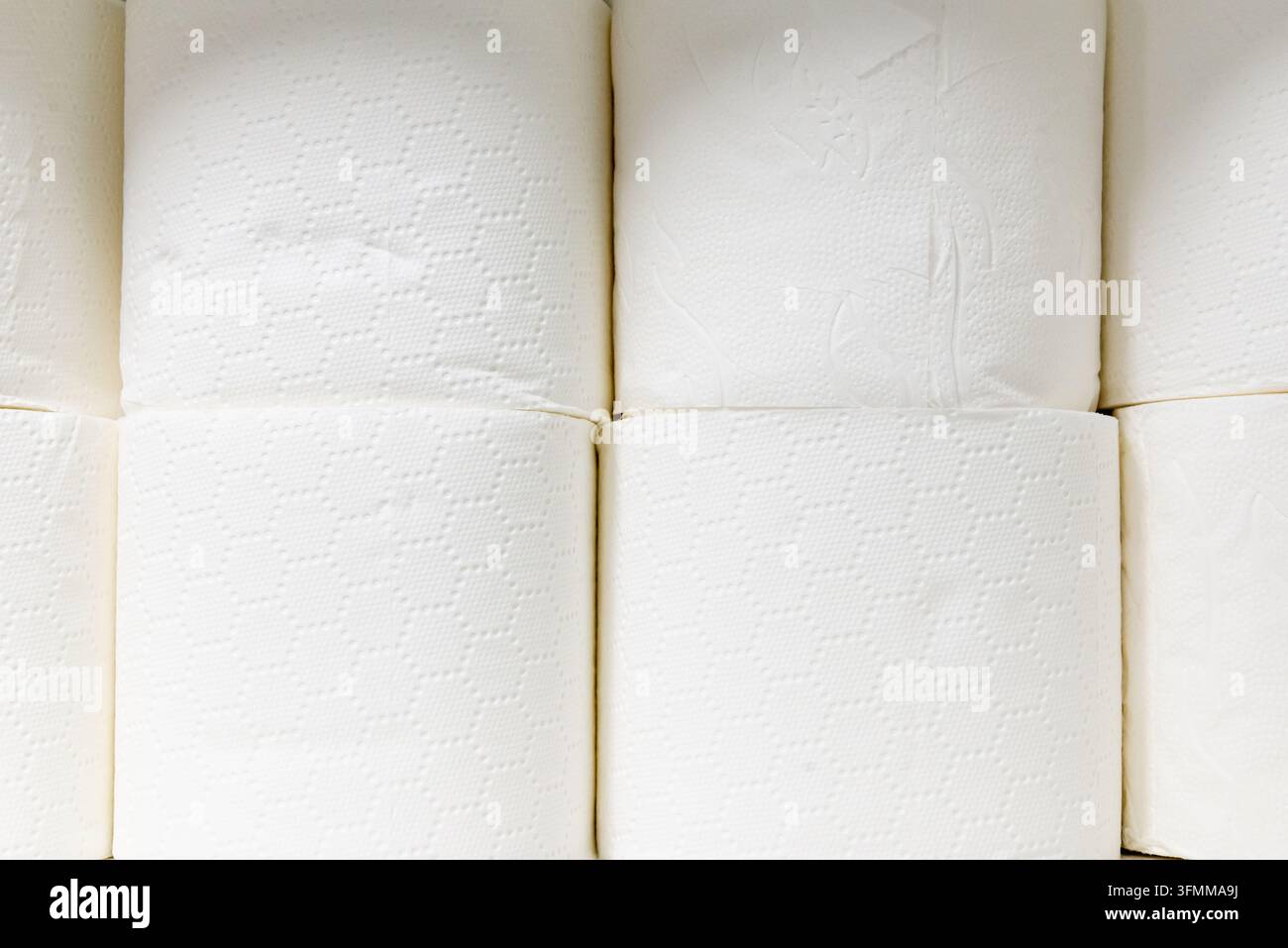 Gestapelte weiße Toilettenpapierrollen mit geprägtem Muster. Stockfoto