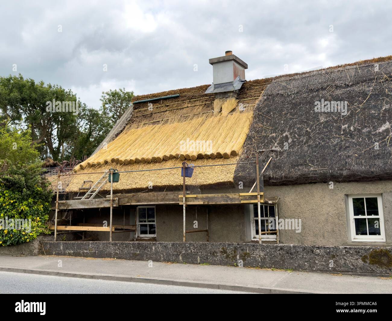 Ein altes Strohdachhaus in der Grafschaft Galway in Irland, dessen Strohdach mit Schilf aus Europa anstatt mit schwer zu beschaffendem langem Stroh erneuert wird Stockfoto