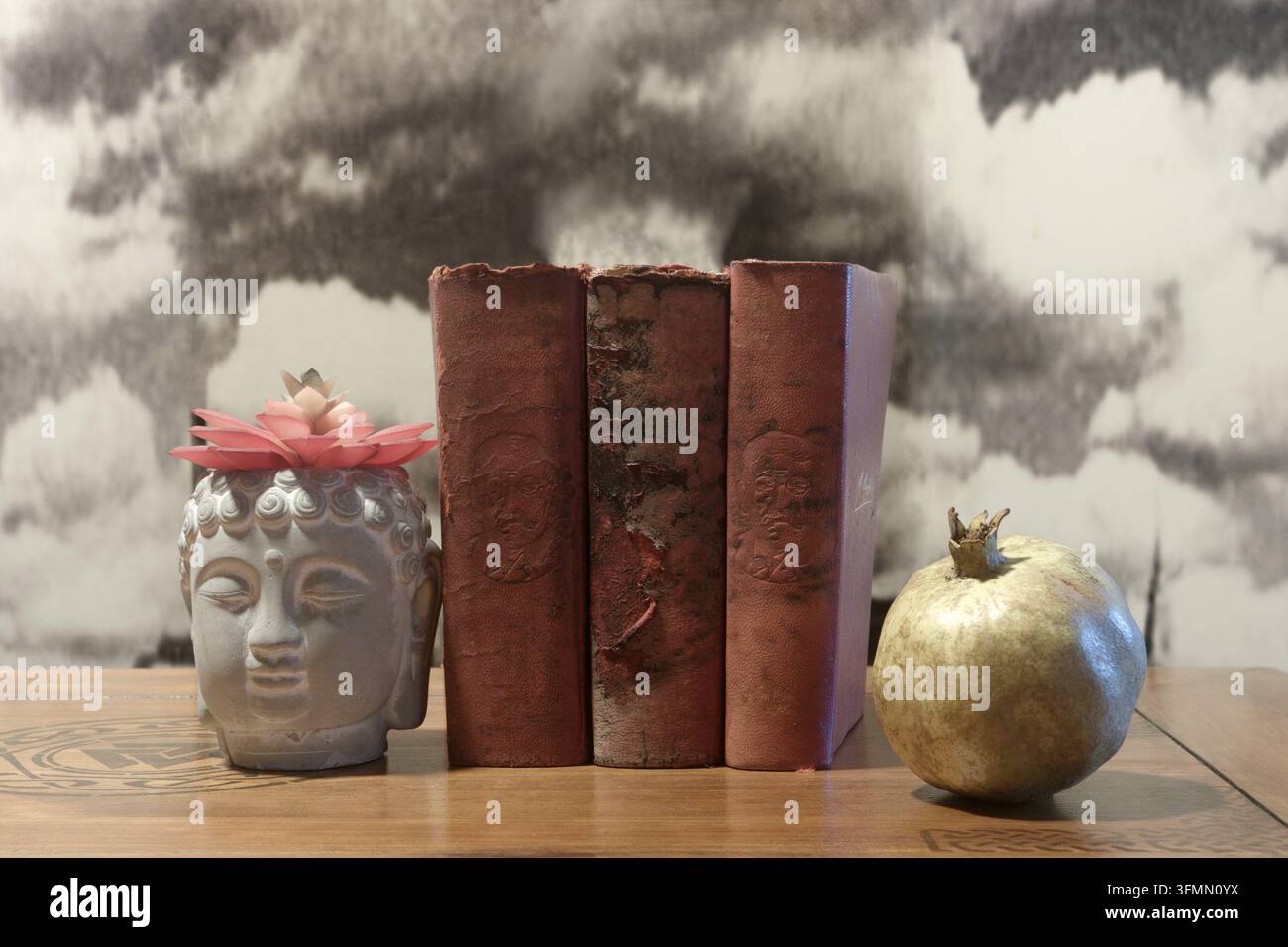 Bücher über hundert Jahre alt; die Buddha-Figur trägt eine Blume auf dem Kopf und hält eine Granatapfel, um die Bücher an Ort und Stelle zu halten. Stockfoto