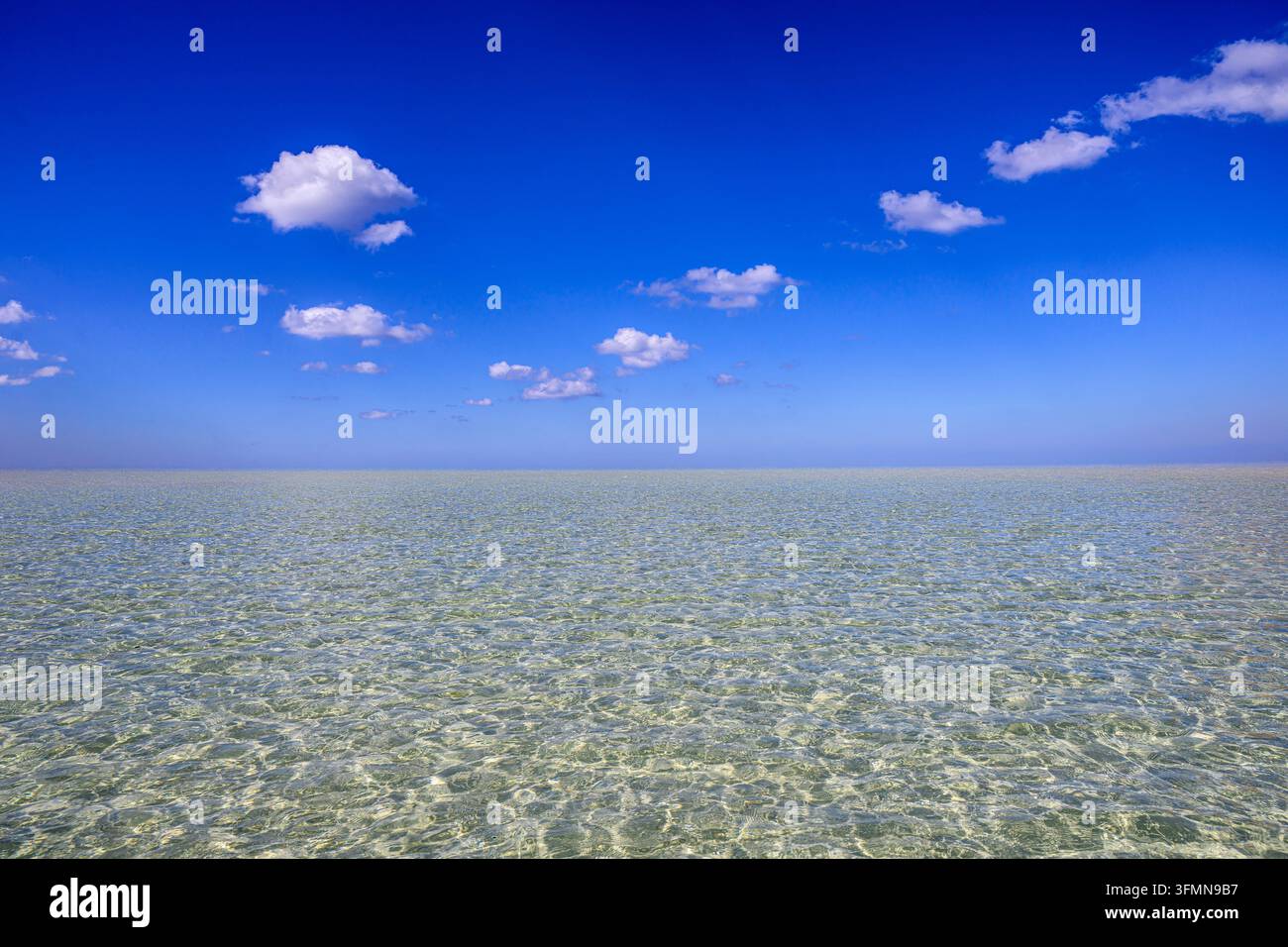 Schöner blauer sonniger Himmel mit flauschigen Wolken über dem klaren türkisfarbenen Meer am Strand Stockfoto
