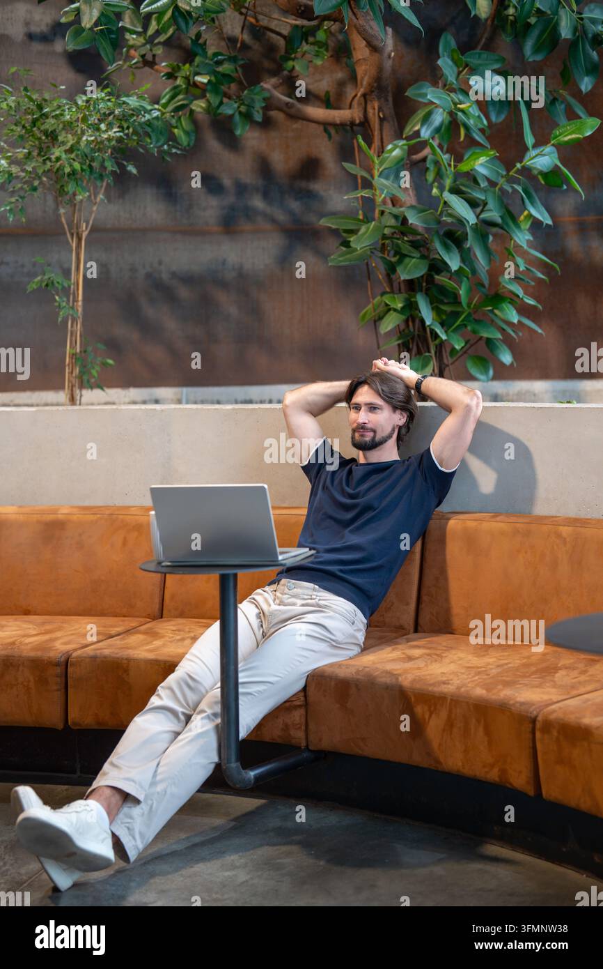Entspannter Geschäftsmann macht Pause nach produktiver Arbeit am Laptop im Café, genießt flexiblen Fernjob Stockfoto