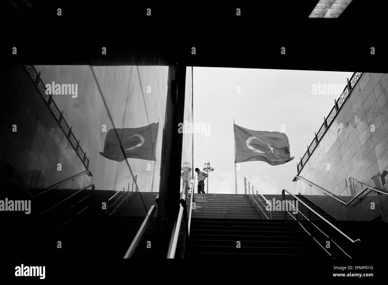 ISTANBUL, TÜRKEI – 4. JULI 2014: Menschen gehen durch den Eingang der Taksim-Metrostation in Istanbul, mit einer großen türkischen Flagge, die ausgestellt ist, Stockfoto