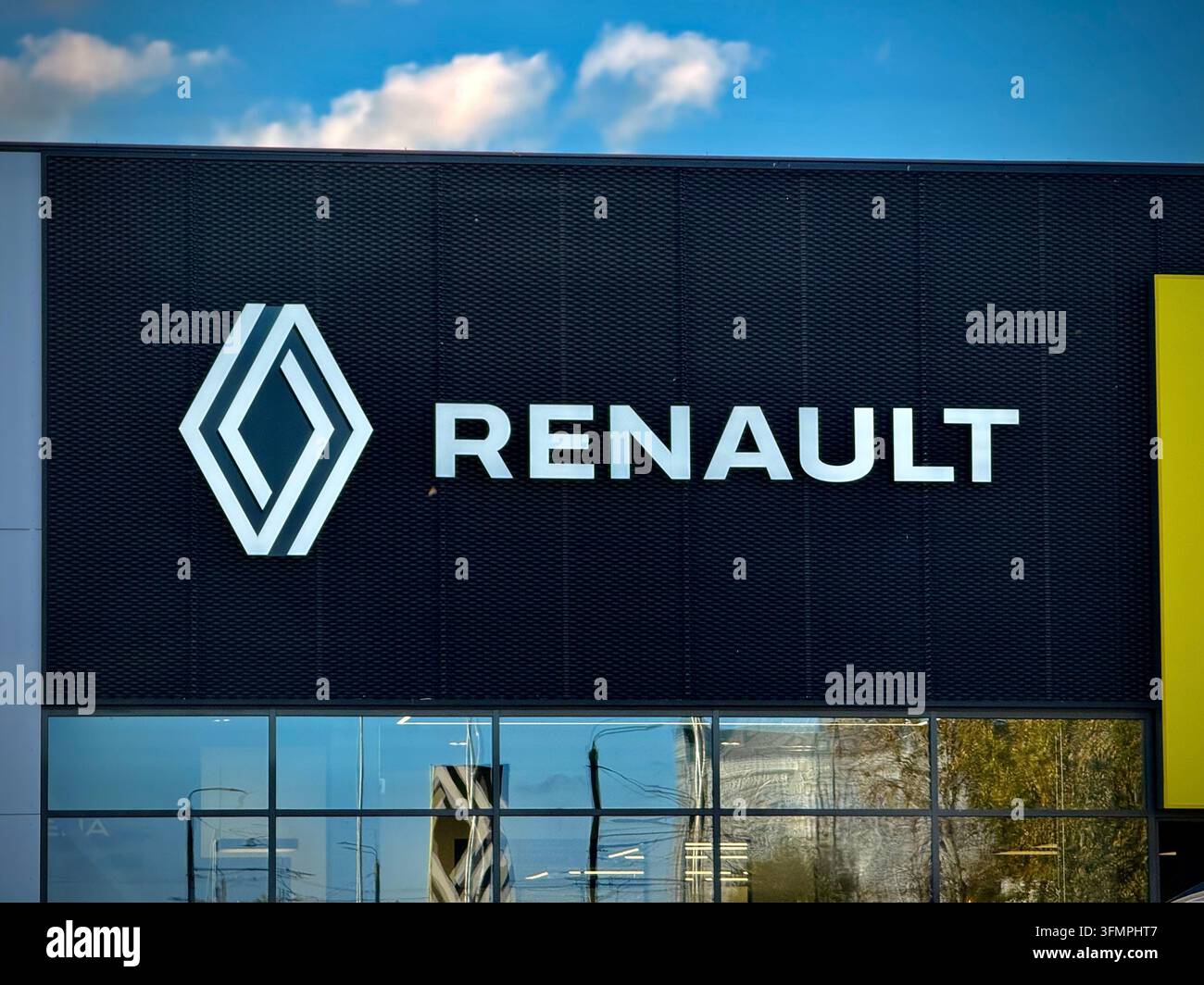 Außenaufnahme eines offiziellen Renault-Autohandels mit einem weißen geometrischen Diamantlogo und Wortmarke auf einer dunklen Netzfassade unter einem klaren blauen Himmel - Smartphone-aufgenommenes Stockfoto
