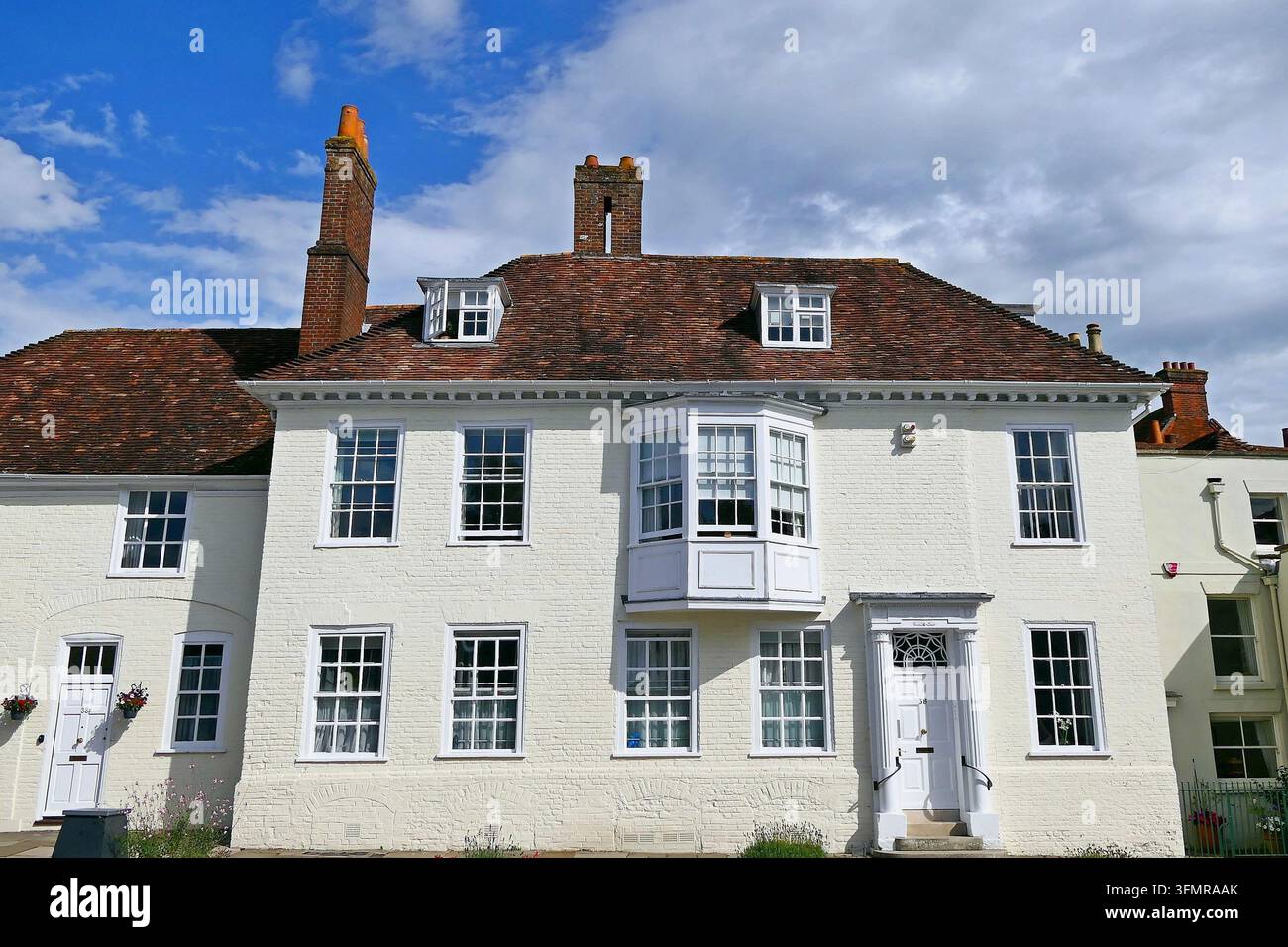 Ein historisches weißes Gebäude mit einem rötlich-braunen Ziegeldach und Schornsteinen in Salisbury, Wiltshire, England Stockfoto
