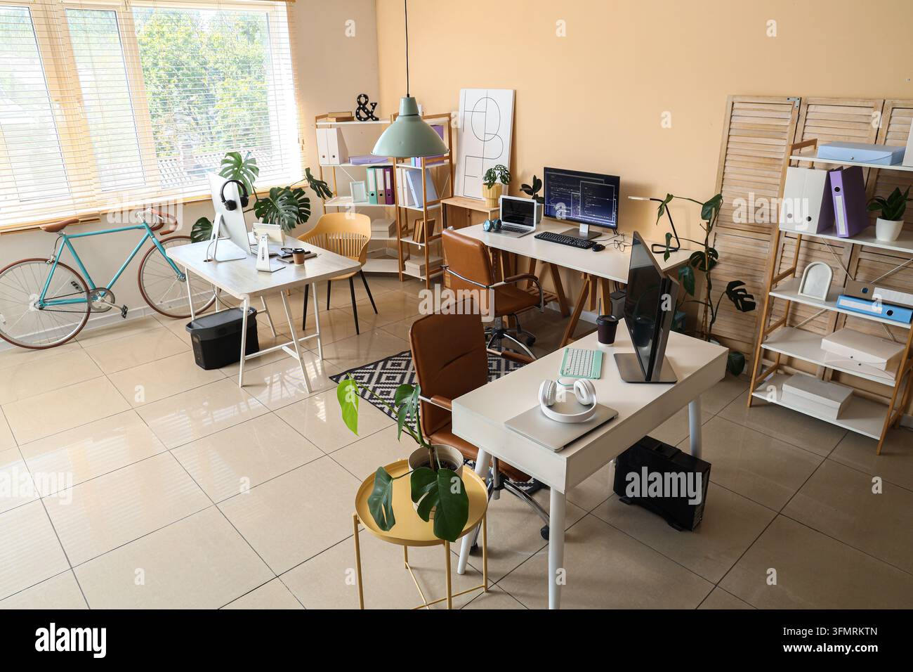 Homeoffice und Coworking-Space, modernes Bürointerieur mit mehreren Schreibtischen für Freiberufler und Digital Nomads in einem hellen Großraumbüro Stockfoto