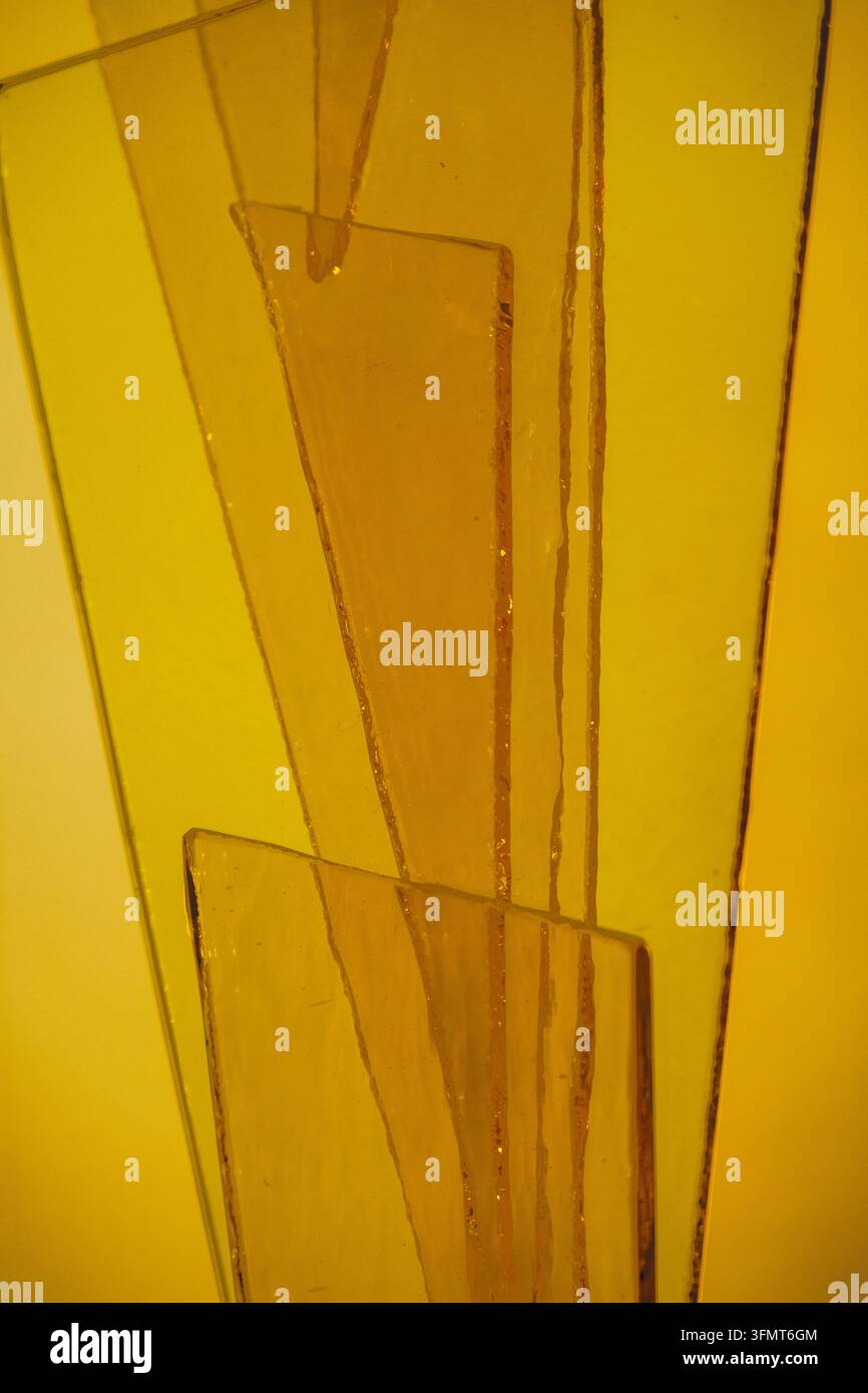 Abstrakte Komposition aus durchscheinenden, sich überlappenden orangefarbenen und gelben Glas- oder Acrylstücken mit unregelmäßigen geometrischen Formen. Schichtungspolygone Platten Stockfoto