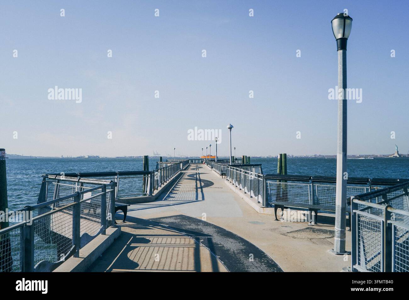 Leerer Valentino-Pier, der an einem sonnigen Tag in Red Hook, Brooklyn, in den New York Harbor hineinreicht, mit offenem Wasser und klarem blauem Himmel. Stockfoto