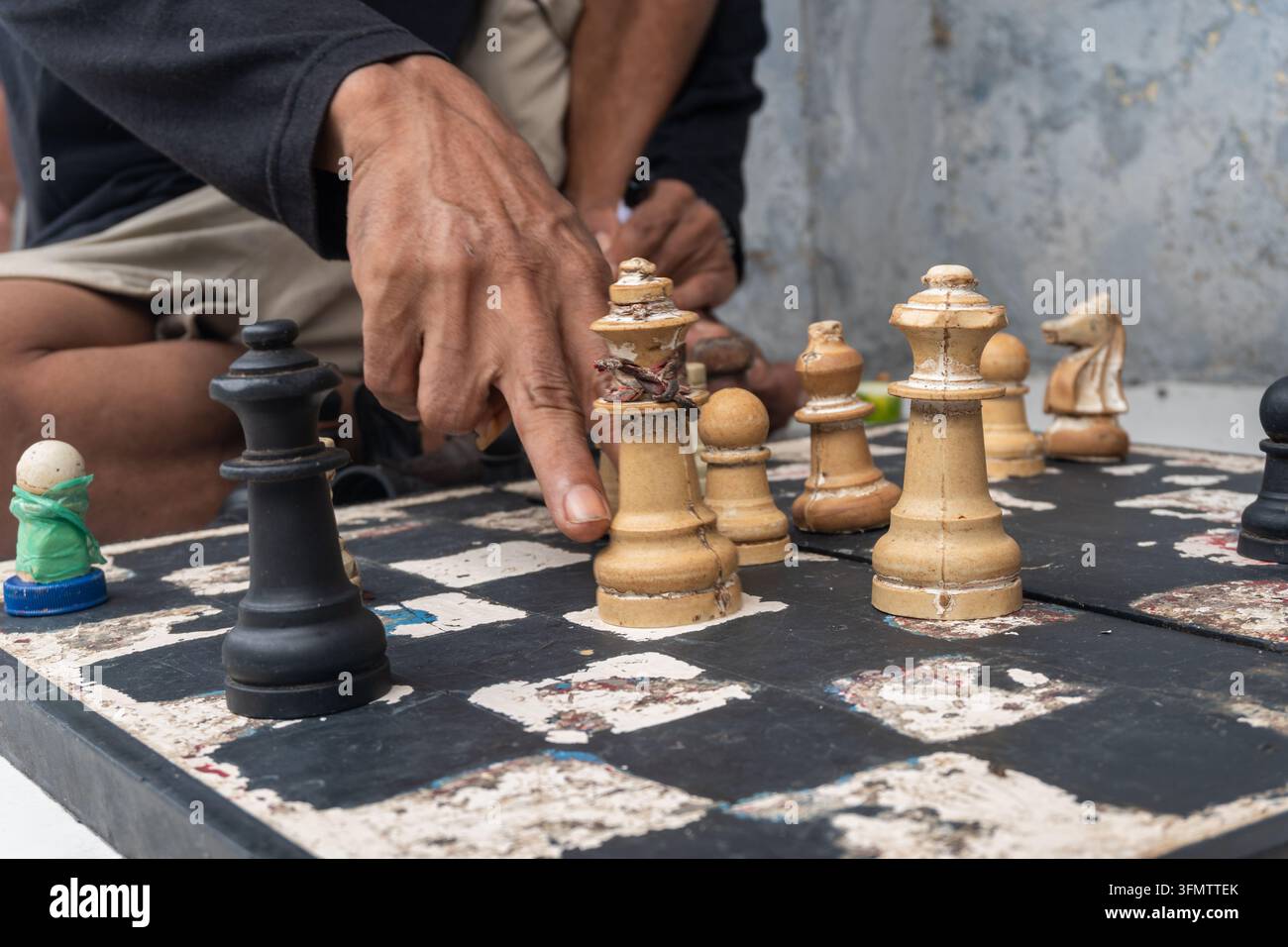 eine Person, die eine Partie Schach auf einem Brett spielt, das auf einem gefliesten Boden aufgestellt ist Stockfoto
