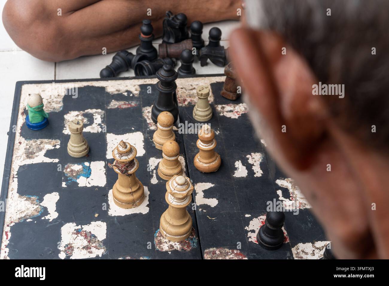 eine Person, die eine Partie Schach auf einem Brett spielt, das auf einem gefliesten Boden aufgestellt ist Stockfoto