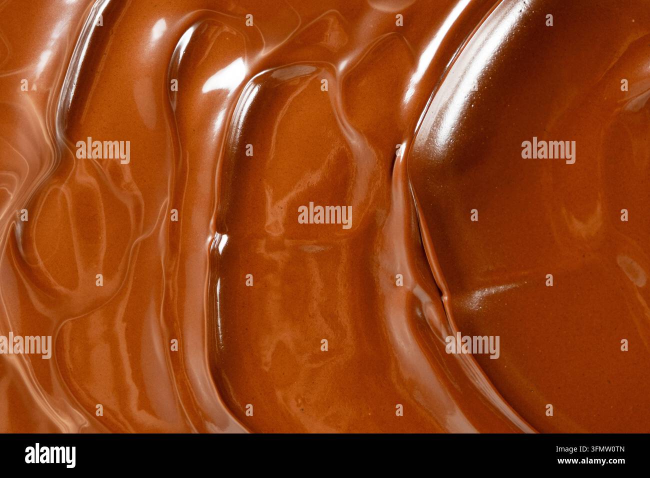 Wirbelnder geschmolzener Milchschokoladenhintergrund mit glänzender Wellenstruktur. Stockfoto
