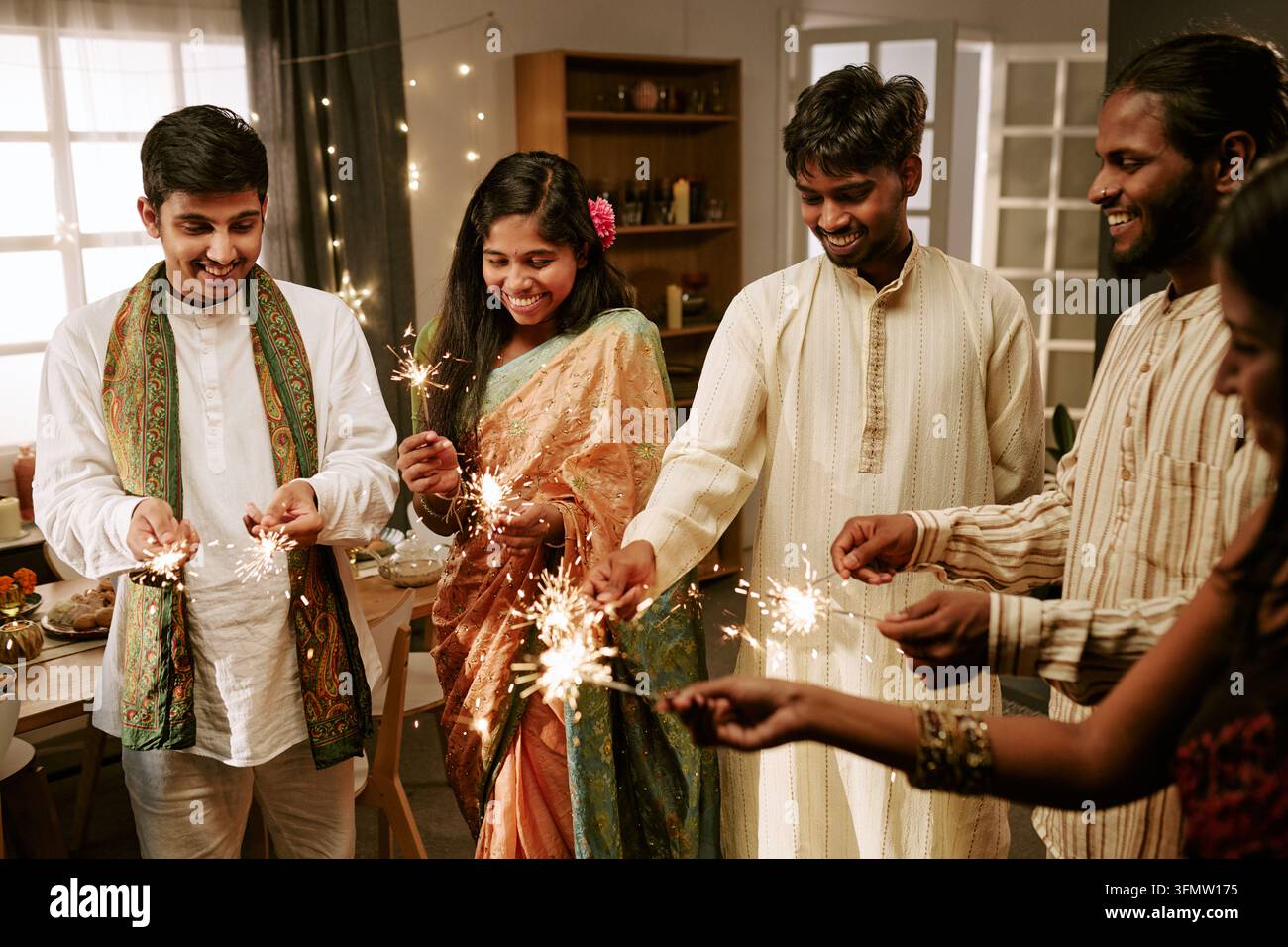 Indische Freunde halten Feuerwerkskörper und feiern drinnen ein Fest Stockfoto