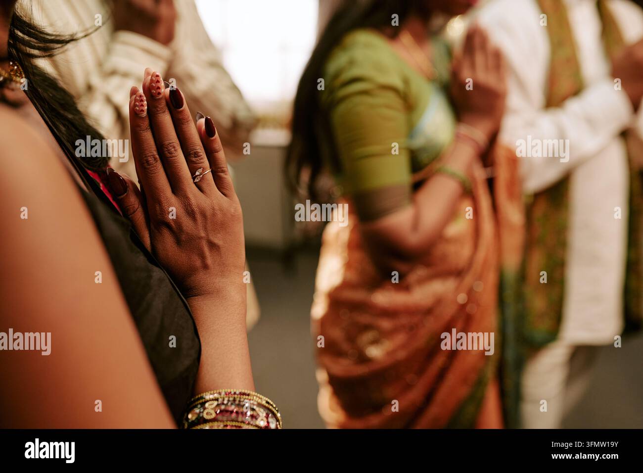 Indische Frau betet mit der Familie während eines Kulturfestes Stockfoto