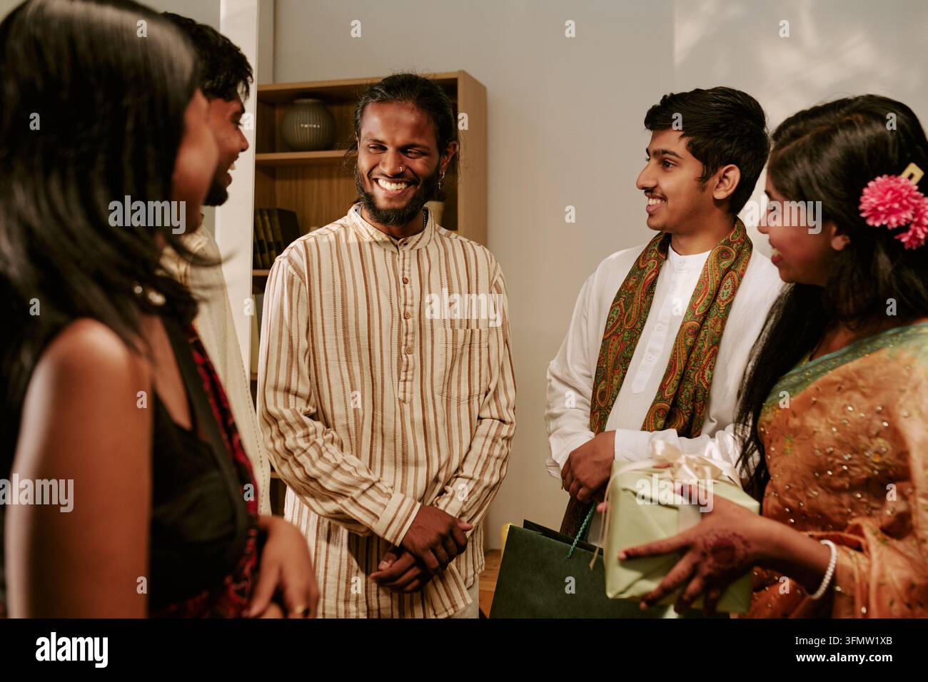 Freudige indische Freunde, die während der Festtagsfeier zu Hause Geschenke austauschen Stockfoto