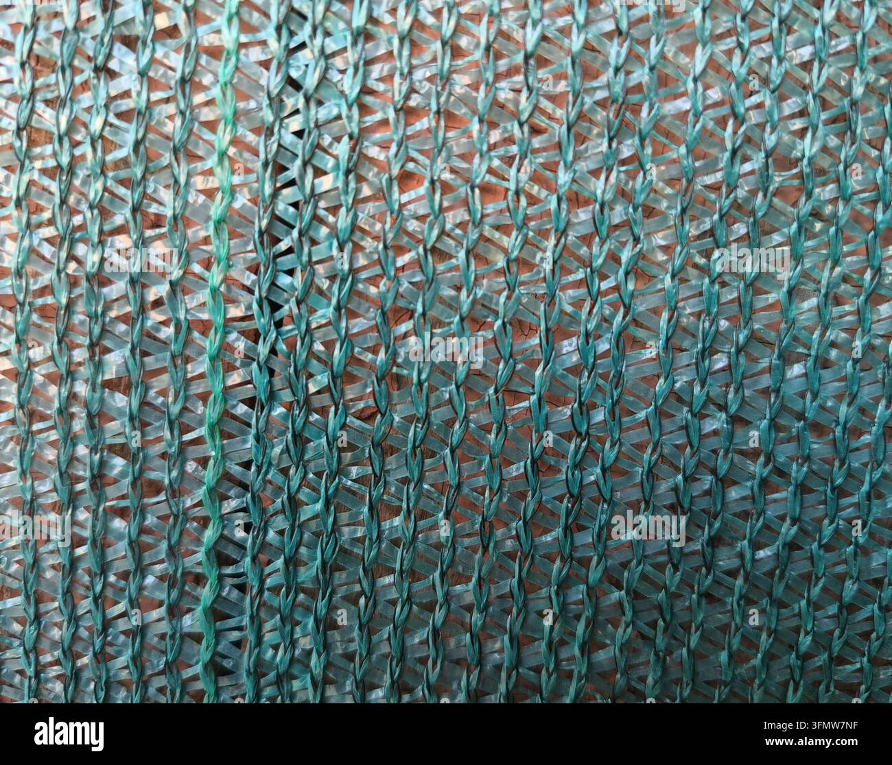 Nahaufnahme eines gewebten türkisfarbenen Kunststoffnetzes, das eine sich wiederholende abstrakte Textur erzeugt Stockfoto