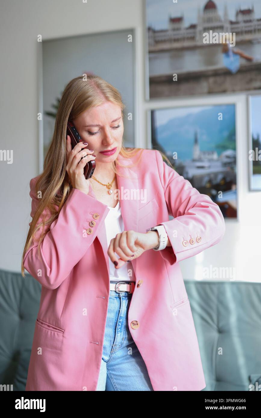 Selbstbewusste Frau in einem rosa Blazer spricht am Telefon, perfekt für Werbeberatung, Online-Geschäft und Karrierenerfolg. Stockfoto