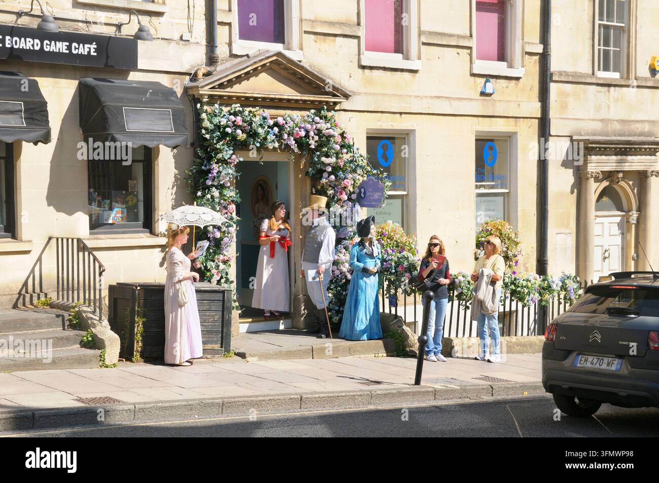 Kostümierte Führer in Kleidung aus der Regency-Zeit stehen im Kontrast zu weiblichen Touristen am Eingang des Jane Austen Centre in Bath, Somerset, England, UK Stockfoto