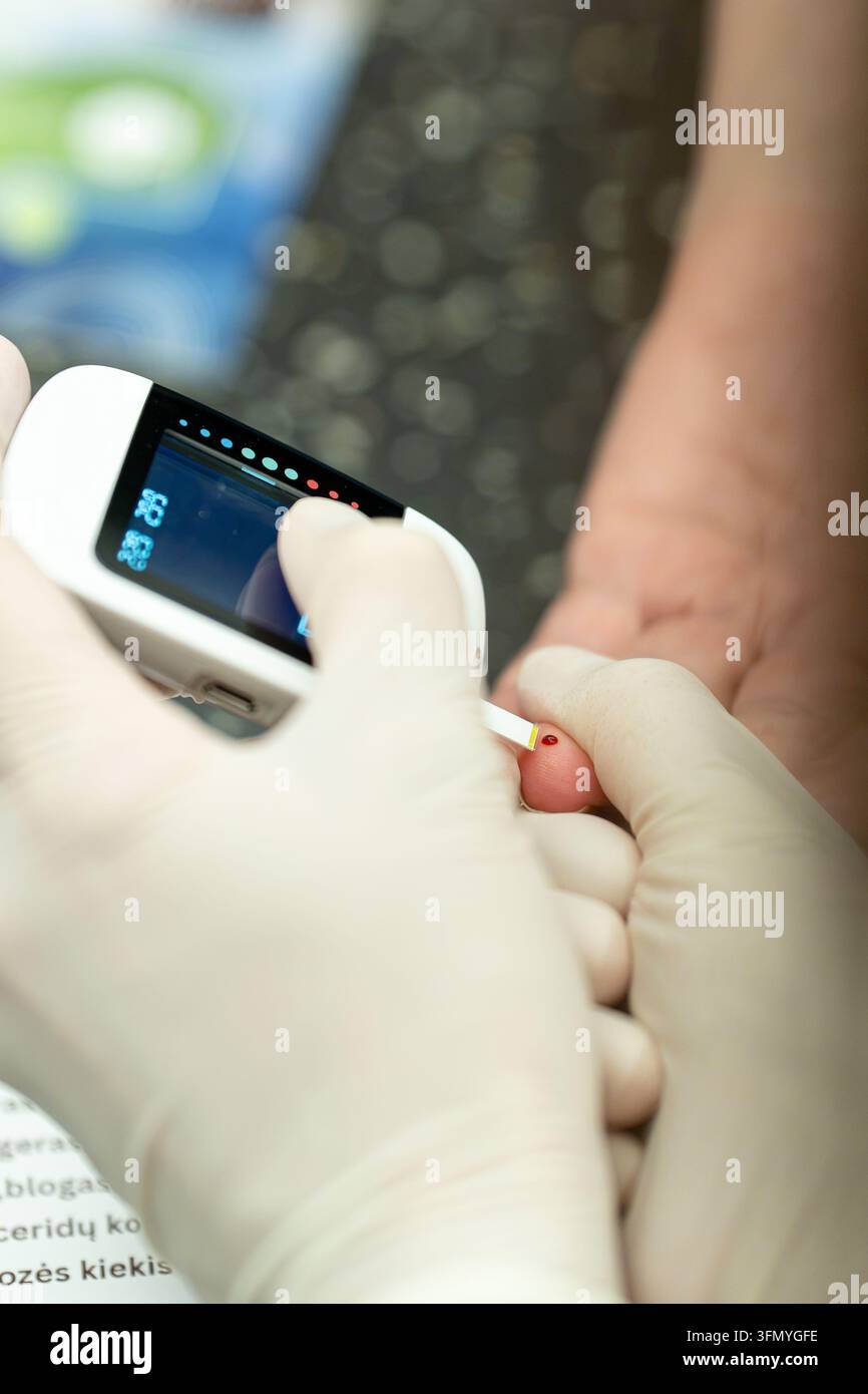 Nahaufnahme einer Krankenschwester, die den Blutzuckerspiegel aus einem Fingerabdruck des Patienten testet, Konzept der Diabetes-Gesundheitsversorgung. Stockfoto
