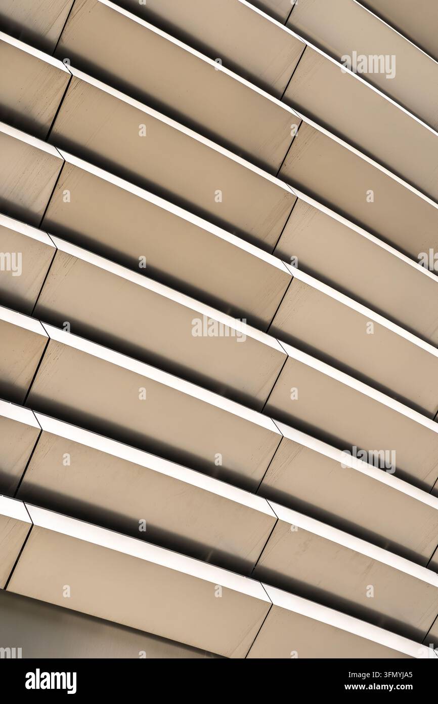 Abstrakte Nahaufnahme einer zeitgenössischen Architekturladung mit diagonalen geometrischen Linien, geschichteten beigen Paneelen und sich wiederholenden strukturellen Elementen in Stockfoto