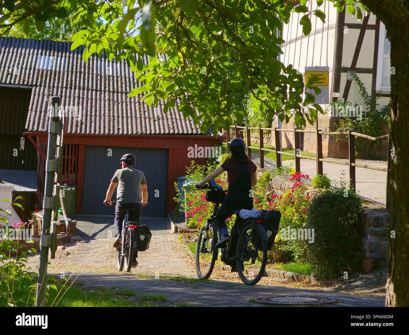 Ein Paar fährt mit dem Fahrrad auf einer ruhigen Straße einer alten deutschen Stadt an einem schönen sonnigen Herbsttag. Stockfoto