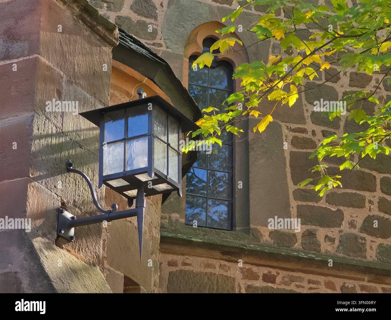Historische antike Wandlaterne, montiert an der Außenwand eines alten Steinkirchengebäudes in Rosenthal, Hessen, Deutschland. - Smartphone-aufgenommenes Stockfoto