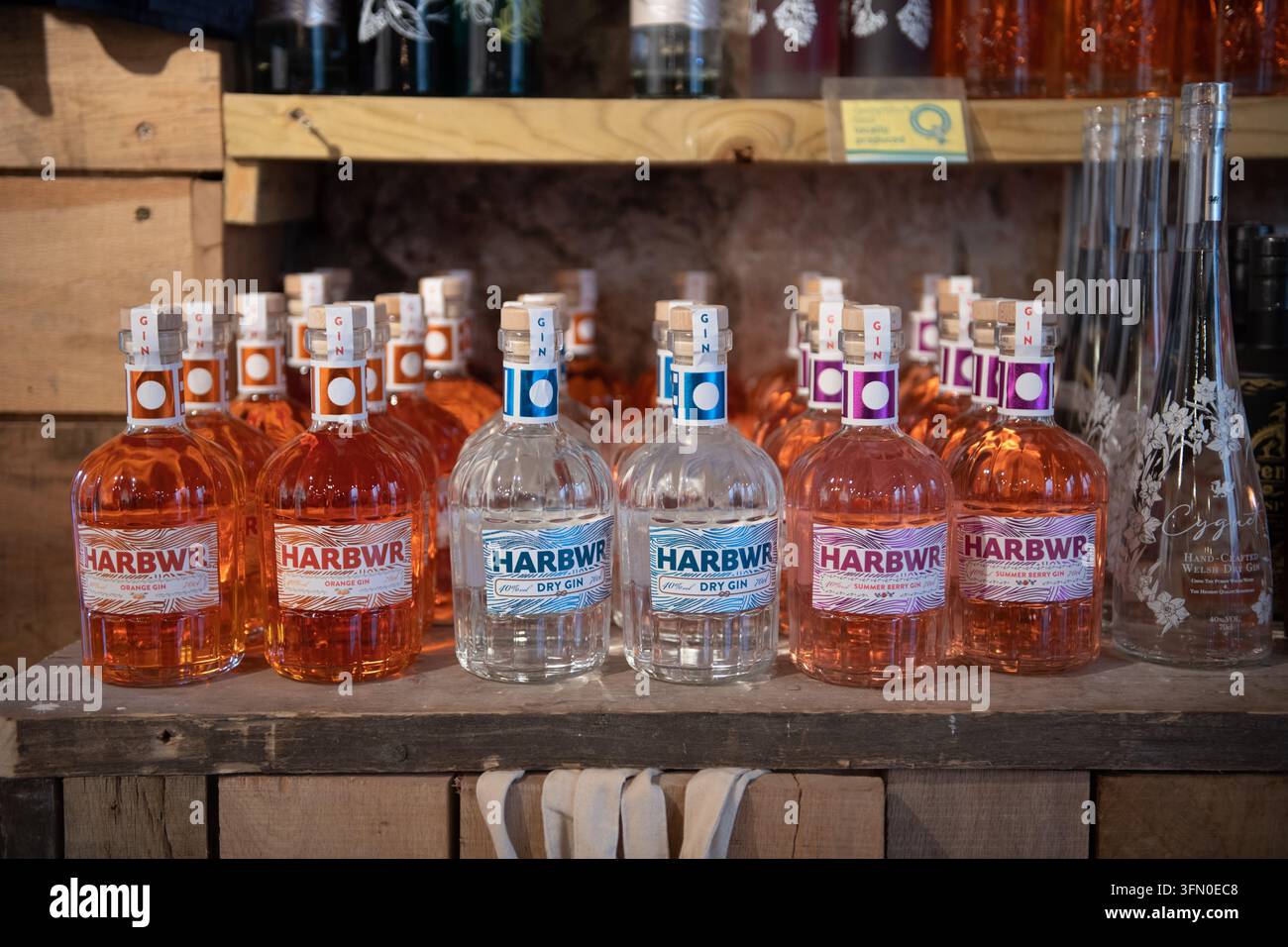 Regale mit Flaschen des lokal produzierten Harbwr Gin, einschließlich der Sorten Orange, Dry und Summer Berry, in Tenby, Pembrokeshire, Wales Stockfoto