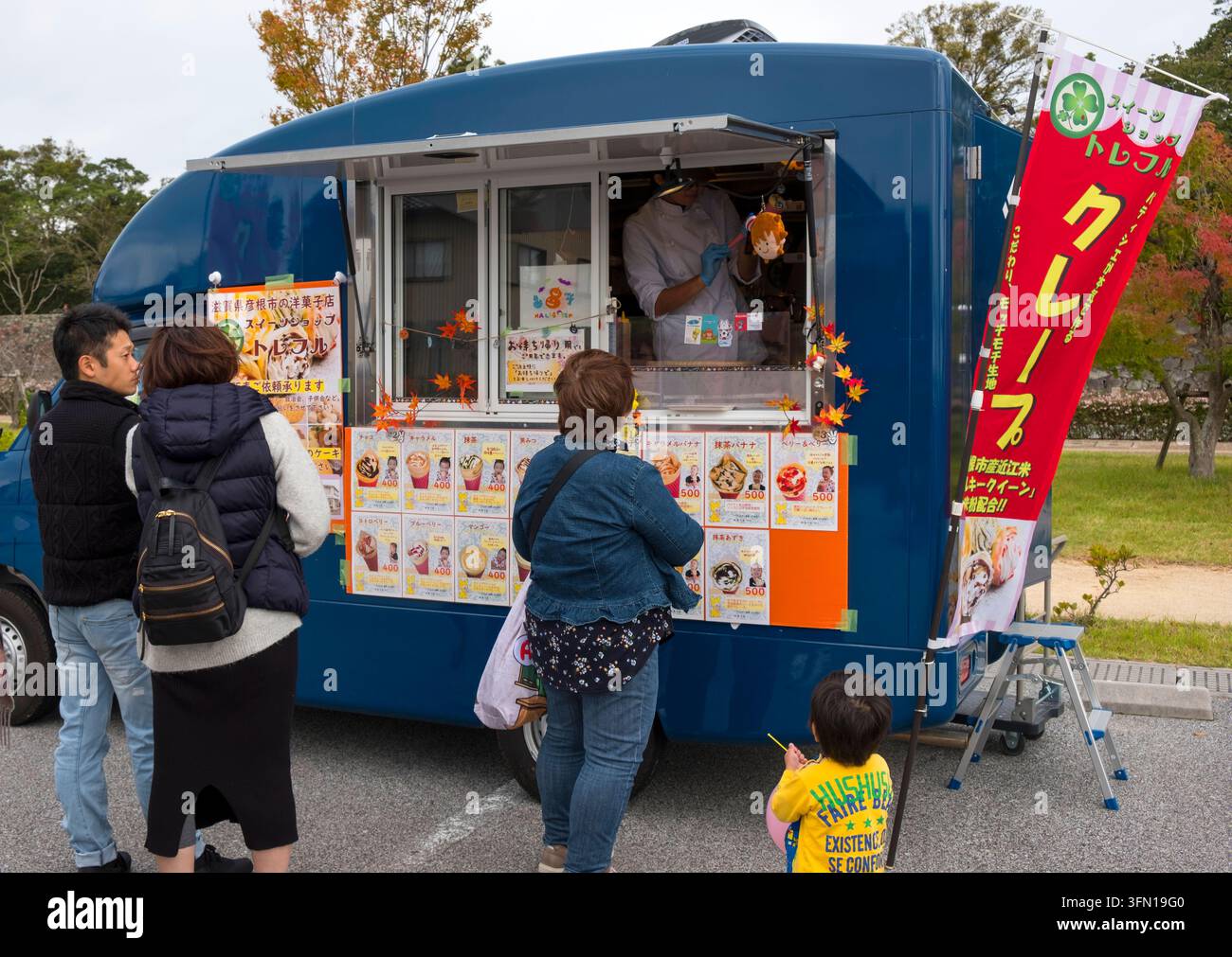 Japanische Kunden stehen in einer Schlange an einem mobilen Imbisswagen, der westliche Süßwaren wie Eiscreme und Crêpes als Dessertleckereien in Hikone, Japan, verkauft. Stockfoto