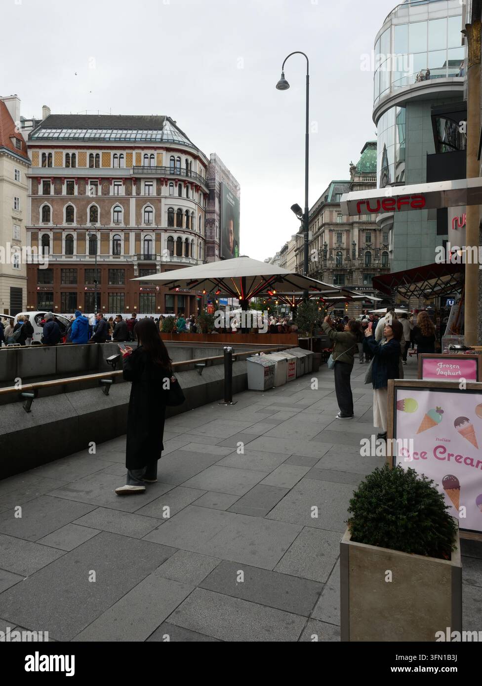 Belebte Fußgänger-Einkaufsstraße, Markt-Sonnenschirme, Fremde gehen in Wien, Österreich. Stockfoto