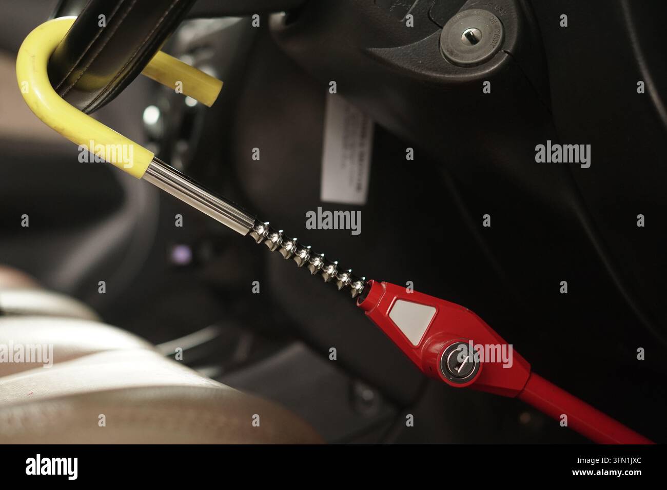 Eine Nahaufnahme einer aus Metall und Kunststoff gefertigten Lenkradsperre, die zur Diebstahlsicherung und Fahrzeugsicherheit an einem Autolenkrad befestigt ist. Stockfoto