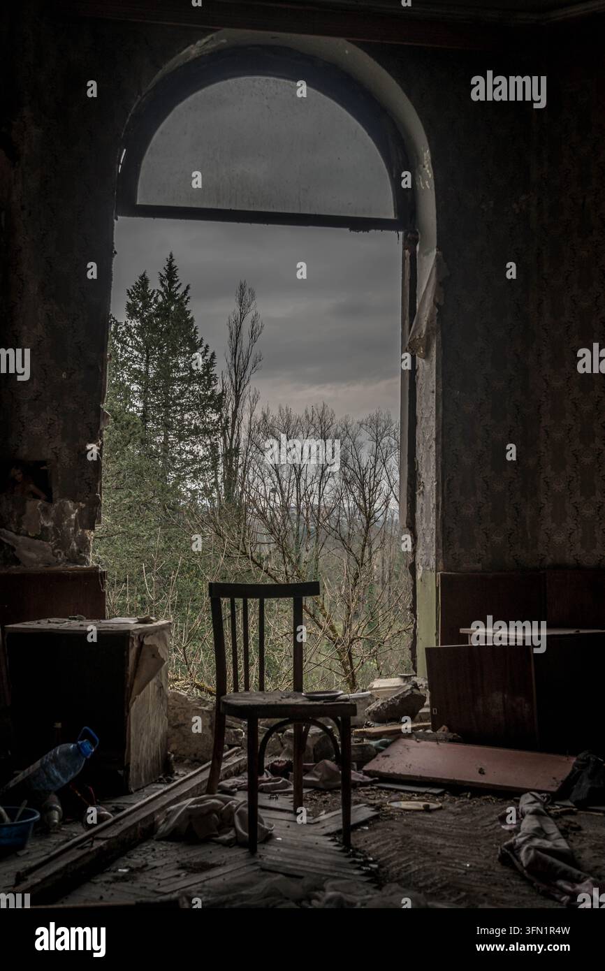 Innenraum eines verlassenen Sanatoriums in Tskaltubo, Georgien, mit einem einsamen Stuhl, umgeben von vergessenen Gegenständen in einem stillen, leeren Raum. Stockfoto